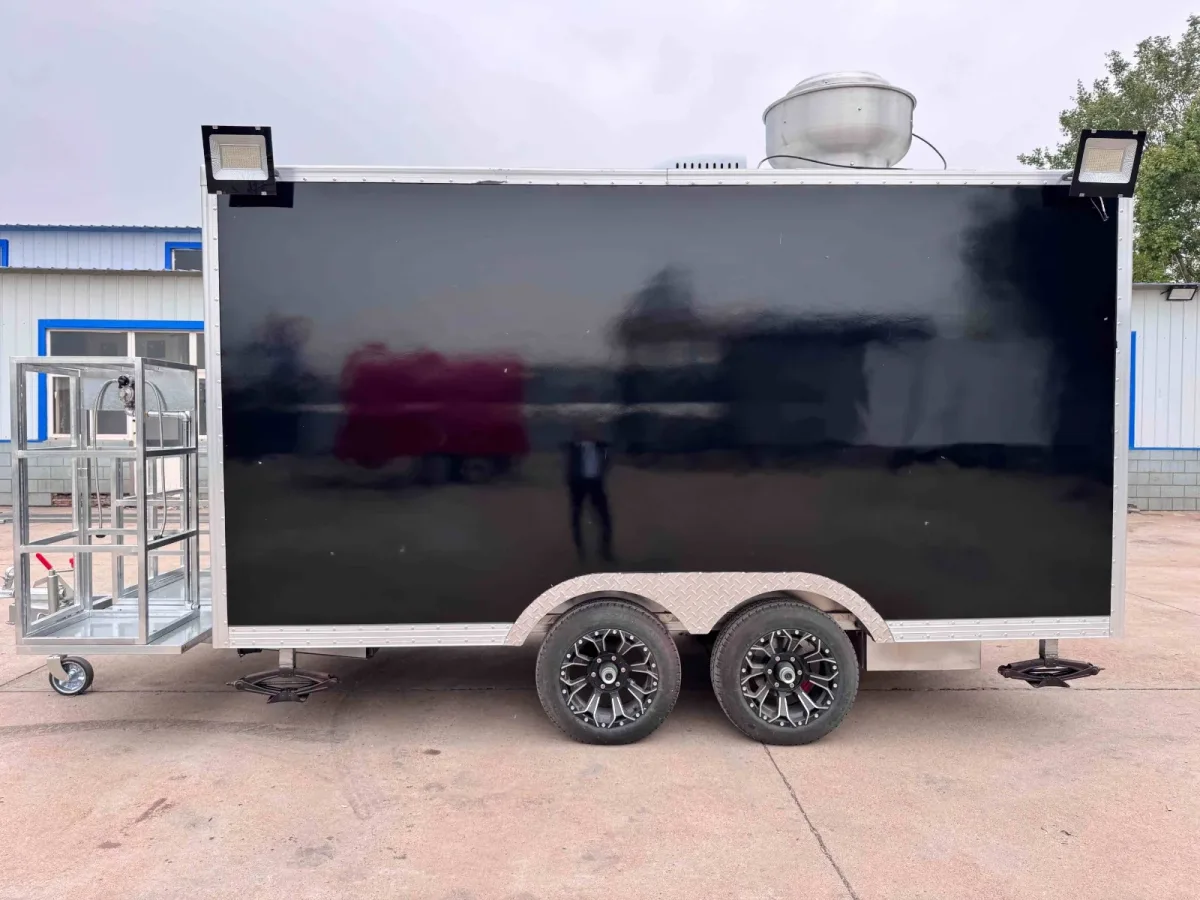 Pizza food trailer: black tandem-axle trailer with rooftop ventilation and work lights, side view