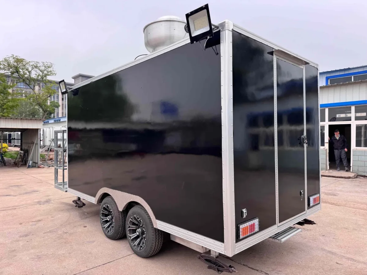 Rear view of a black tandem-axle pizza food trailer with a rear door and roof exhaust